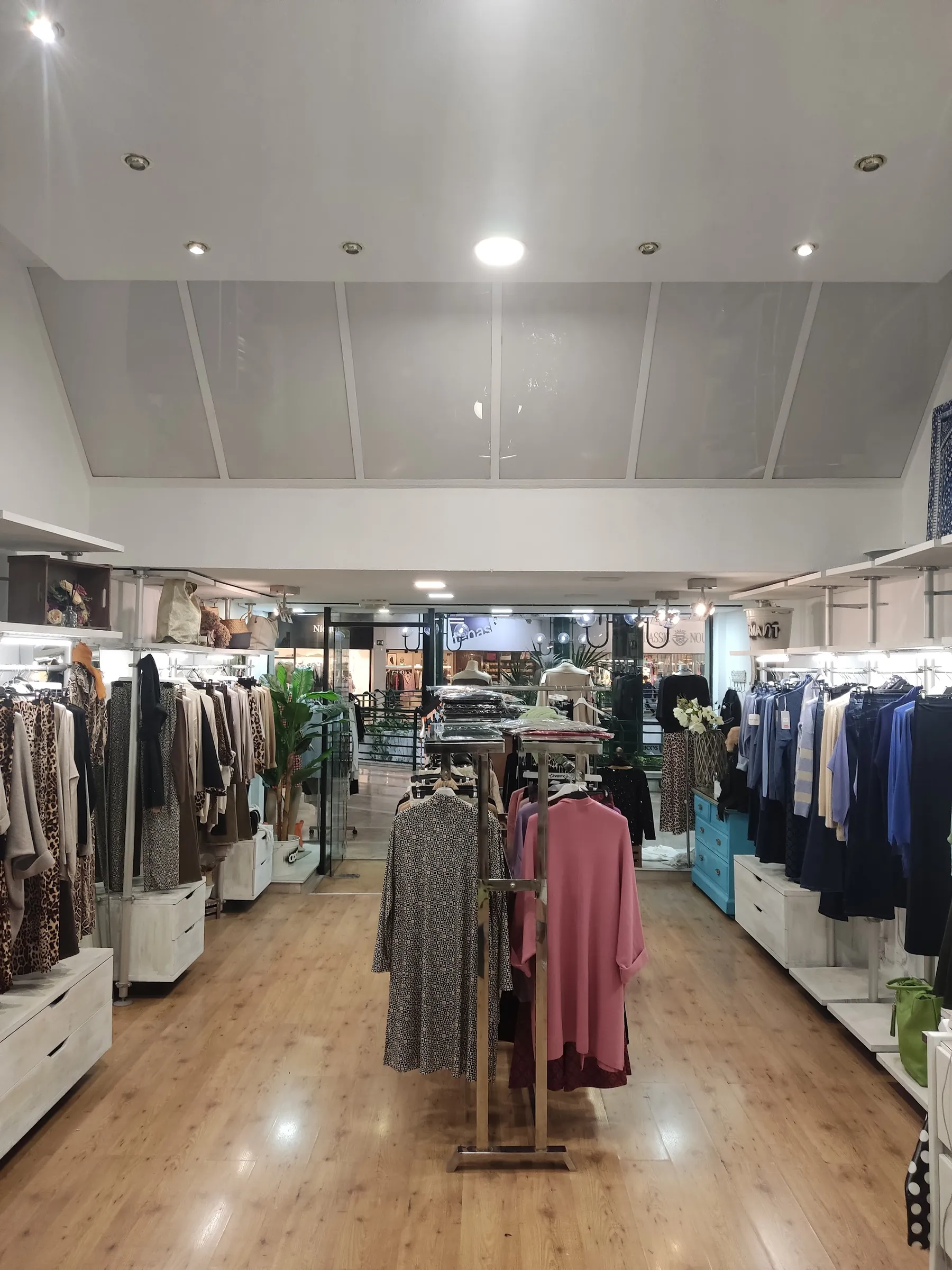 El interior de Modas Charmant: percheros a los dos lados, suelo de madera y la salida al fondo